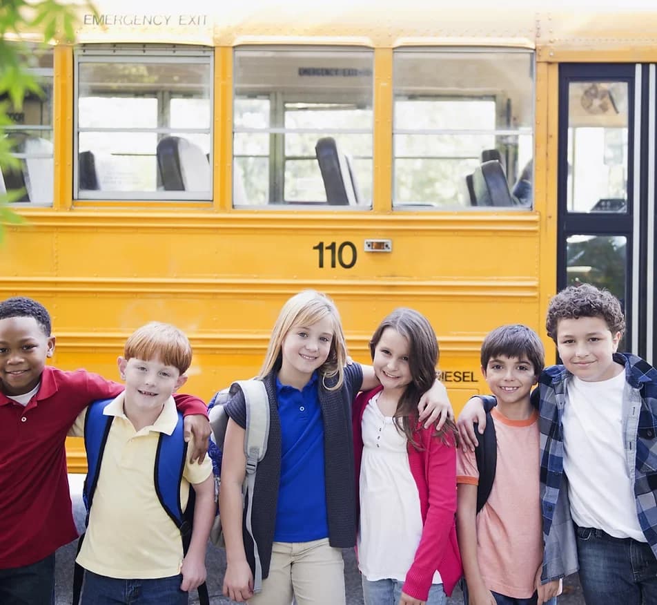 School children standing beside a school bus