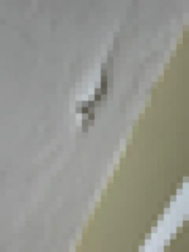 Peeling textured finish along a white interior ceiling edge.
