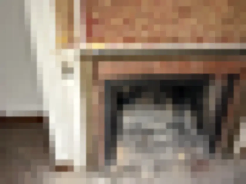 Brick fireplace with dark interior and broken hearth fragments