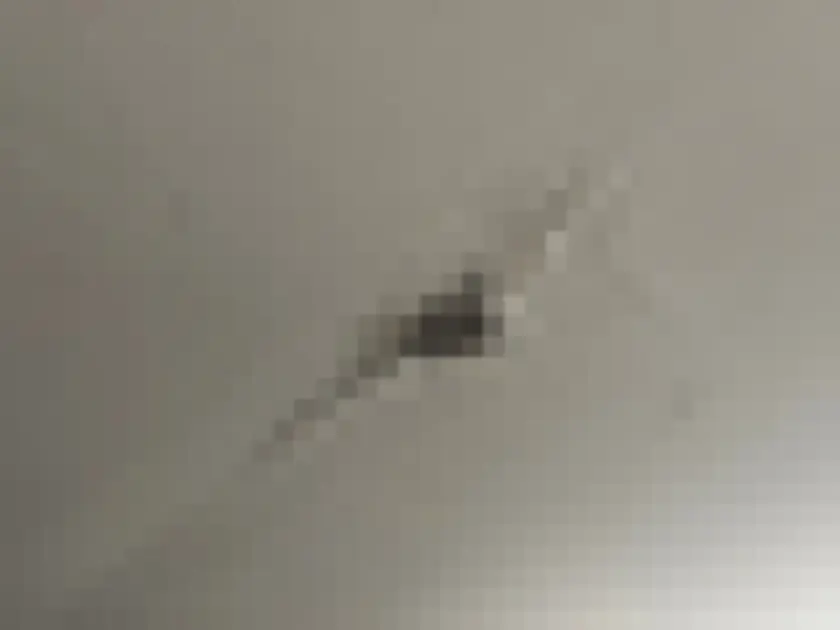 Small peeling area in ceiling finish near a fitting.