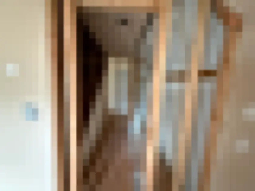 Narrow interior hallway with wallboards removed to reveal timber studs.