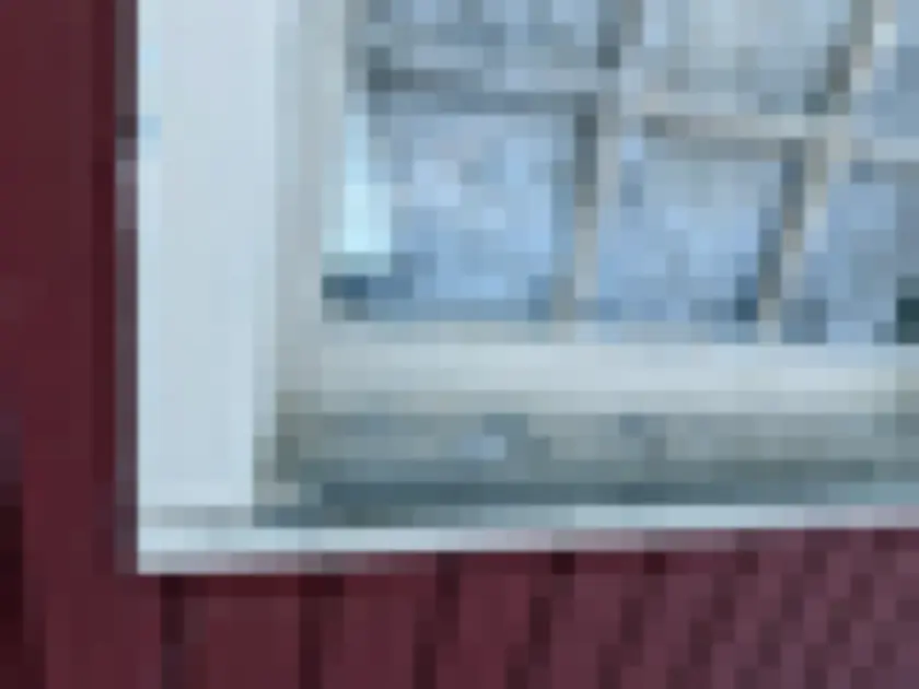 Photograph of peeling paint on white exterior window sill or sash close-up