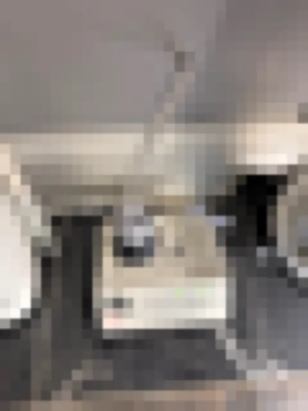 Photograph showing portable cylindrical air sampler with upright holder on dark tiled floor near plumbing fixtures