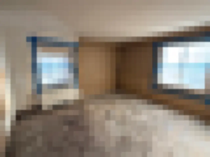 Photograph showing unfurnished room with protective blue tape and plastic at windows